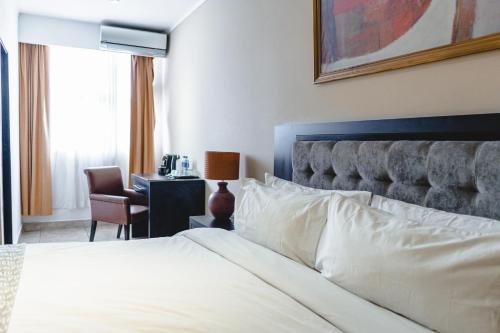 a bedroom with a bed and a desk with a chair at KC Hotel San Jose in San José