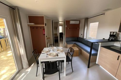 eine kleine Küche und ein Esszimmer mit einem Tisch und Stühlen in der Unterkunft Mobile Home OuiReves 113 facing the Mediterranean in Sète