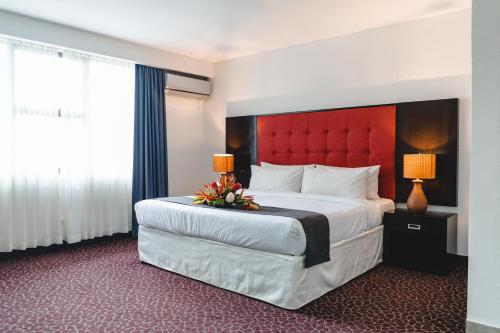 a hotel room with a large bed with a red headboard at KC Hotel San Jose in San José