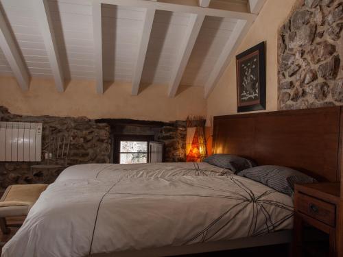 a bedroom with a large bed and a stone wall at Casa Rural La Ardina in Sotres