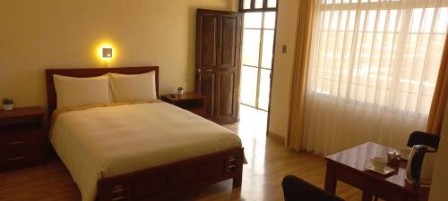 a bedroom with a bed and a desk and a window at Hotel CESARE in Uyuni