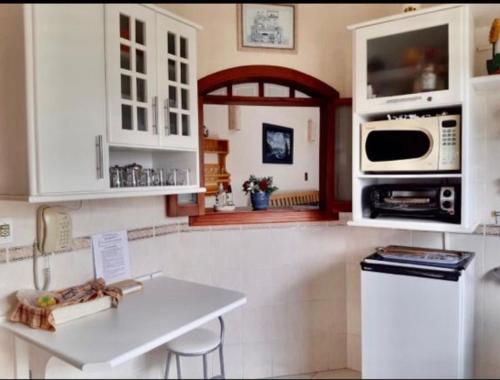 a kitchen with white cabinets and a sink and a microwave at Piemonte Flat Serra Negra in Serra Negra