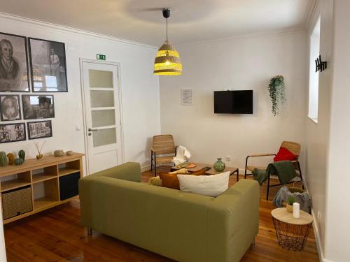 a living room with a green couch and a tv at Memórias de Setúbal AL in Setúbal