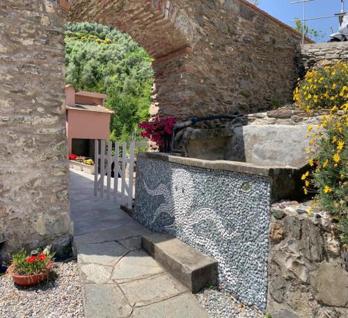 a stone wall with an archway and stairs in a yard at La camera del mulino in Levanto