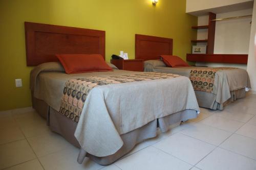 two beds in a room with green walls at Concierge Plaza La Villa in Colima