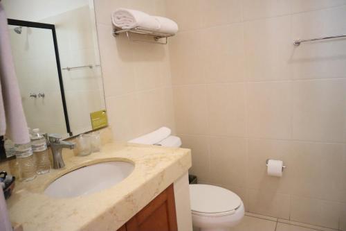 a bathroom with a sink and a toilet and a mirror at Concierge Plaza La Villa in Colima