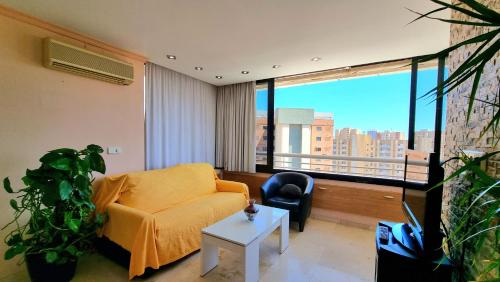 ein Wohnzimmer mit einem gelben Sofa und einem großen Fenster in der Unterkunft Precioso apartamento con vistas al mar in Benidorm