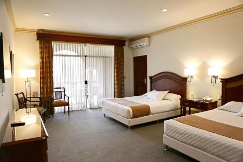 a hotel room with two beds and a window at Hotel Los Parrales in Tarija