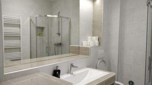 a white bathroom with a sink and a mirror at Apartments Town Center in Sarajevo