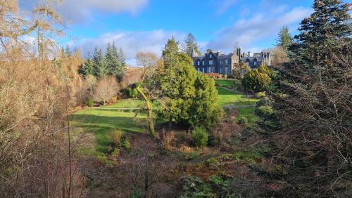 a house on a hill with trees in the foreground at Glencruitten House in Oban