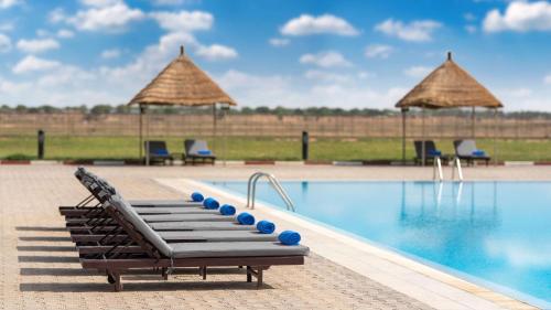 a pool at a resort with lounge chairs and umbrellas at Radisson Blu Hotel N'Djamena in NʼDjamena