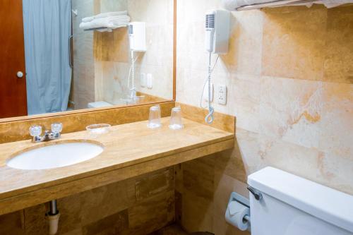a bathroom with a sink and a mirror and a toilet at Hotel Carmel in Lima