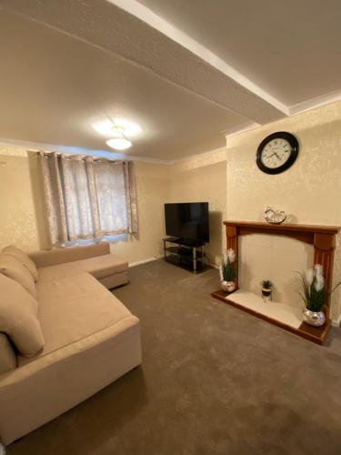 a living room with a couch and a clock on the wall at Dunfermline, 2 bedroom home free on street parking in Fife