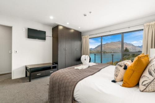 a bedroom with a large bed and a large window at Lakefront Penthouse Apartment with 270-degree view in Queenstown