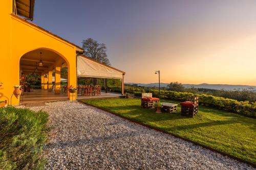 ein gelbes Gebäude mit einer Terrasse und Gras in der Unterkunft Tenuta Risalpiano in Pelago