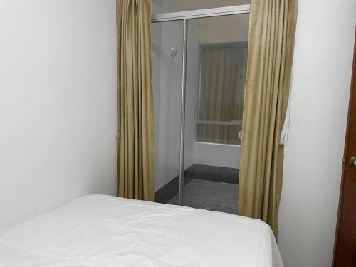 a bedroom with a white bed and a shower at Apartamento en el Centro de Trujillo - Primer Piso in Trujillo