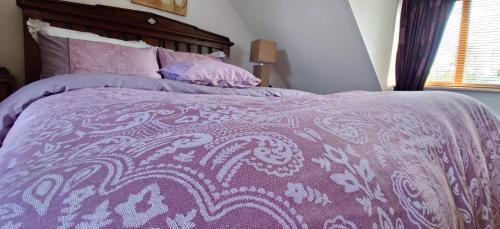 a purple bed with a purple and white comforter at 'Neasa' Luxury Double Bedroom in Foxford