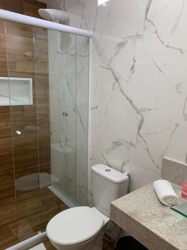 a white bathroom with a toilet and a shower at Lila Limao Hostel in Abraão