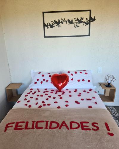 a red heart sitting on a bed with red petals at Bangalôs da Montanha in Serra do Cipo