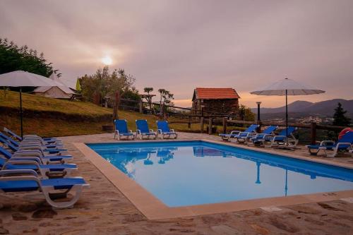 a swimming pool with chairs and umbrellas at Arrabia Casa da Eira in Raiva