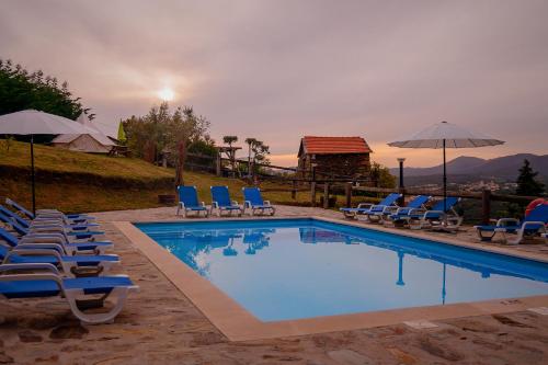 a swimming pool with chairs and umbrellas at Arrabia Casa da Eira in Raiva