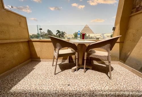 a small balcony with a table and two chairs at Giza Pyramids View Inn in Cairo