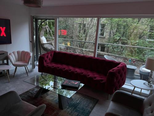 a living room with a red couch and a glass table at DESIGNER HOUSE - University of Glasgow / Central Glasgow 'Hillhead' West End G12 - Luxurious & Contemporary Detached House / Terrace / Garden / 'electric car charging' Garage Parking in Glasgow