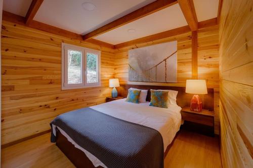 1 Schlafzimmer mit Holzwänden und 1 Bett mit 2 Lampen in der Unterkunft Arrabia Bunga Payva in Raiva