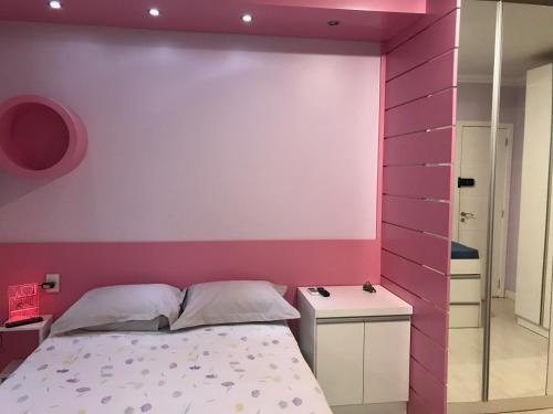 a bedroom with a pink wall and a bed at Conforto entre a UFSM e o centro in Santa Maria