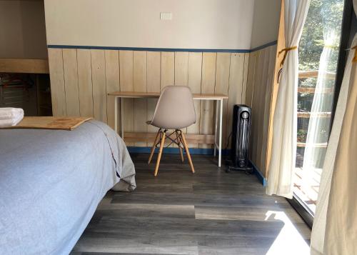 a bedroom with a bed and a chair next to a window at La Colmena eco lodge in Ensenada