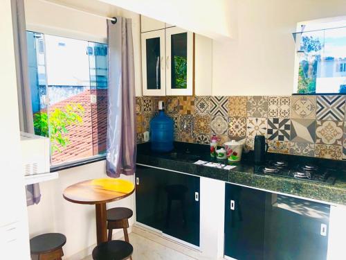 a kitchen with a counter and a table and some windows at FLAT / APARTAMENTO NA PRAIA DO FORTE in Cabo Frio