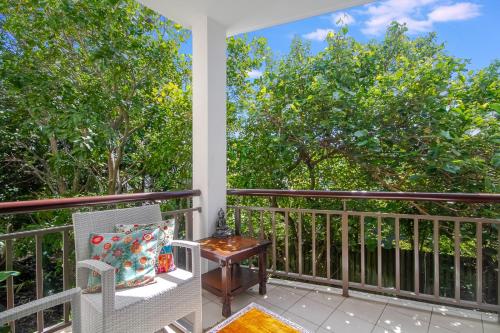 a balcony with a chair and a table and trees at 241 Santai - Balinese Resort Apartment by uHoliday in Casuarina