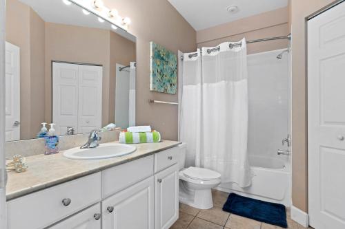 y baño con lavabo, aseo y ducha. en Charming Townhouse with 2 King Suites & Amazing Pool only 10 Mins to Disney, en Kissimmee