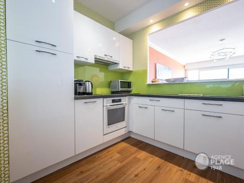 une cuisine avec des armoires blanches et des murs verts dans l'établissement Appartement moderne 80m² avec wifi, lave-vaisselle, balcon et vue mer - FR-1-197-539, à Les Sables-dʼOlonne