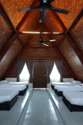 een kamer met een plafondventilator en een rij bedden bij SENTA Adventure Camp & Resort in Kampong Minyak Beku