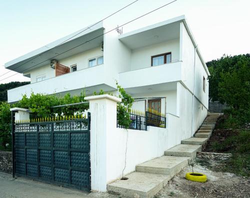 a white house with a black gate and a yellow frisbee at Patio Rooms Gjirokaster in Gjirokastër
