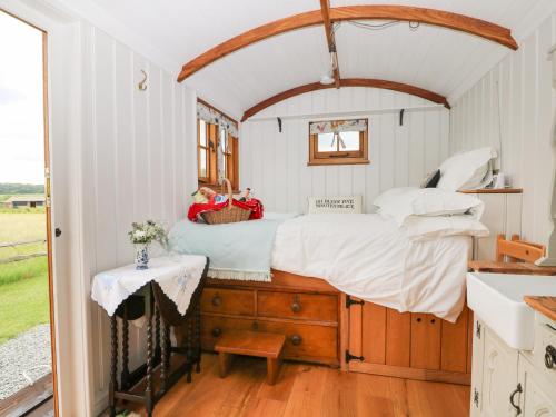 a bed in a small room with a table at Shepherds Hut in Lewes