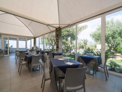 GasponiにあるBelvilla by OYO Casa Vacanza Villa Garden Biloのテーブルと椅子、大きな窓のあるレストラン