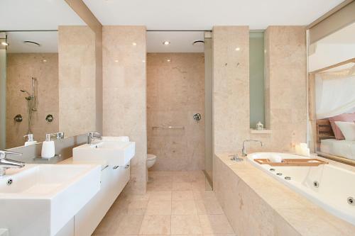 a bathroom with two sinks and a tub and a toilet at 128 Santai - Stylish Resort Apartment by uHoliday in Casuarina