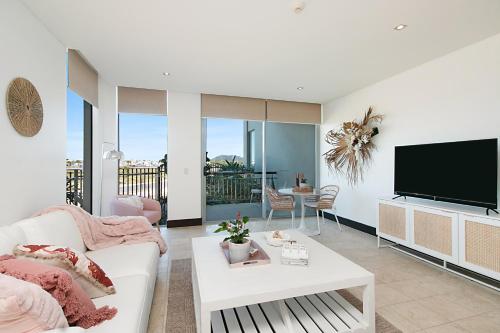 a living room with a white couch and a flat screen tv at 128 Santai - Stylish Resort Apartment by uHoliday in Casuarina