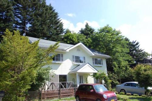a white house with a red car parked in front of it at ヴィラコテージ Chaconne Karuizawa in Karuizawa