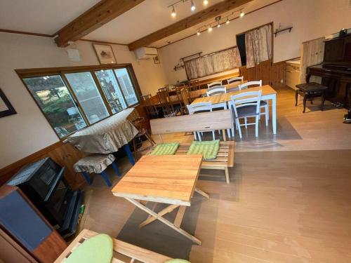 a room with tables and chairs and a piano at ヴィラコテージ Chaconne Karuizawa in Karuizawa