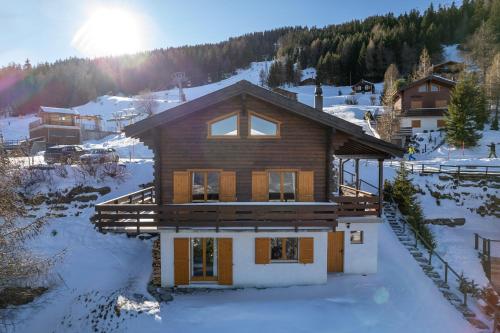 a house in the snow with the sun in the background at Chalet OnThePiste in La Tzoumaz