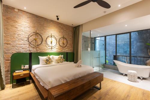 a bedroom with a large bed and a bathtub at Seaforest Hotel by Haviland in Da Nang