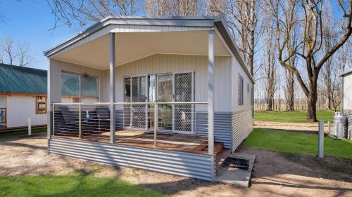 a tiny house with a porch in a yard at Colac Colac Caravan Park in Corryong