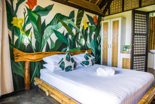 a bedroom with a bed with a mural of flowers at Fox & The Firefly Cottages in Loboc