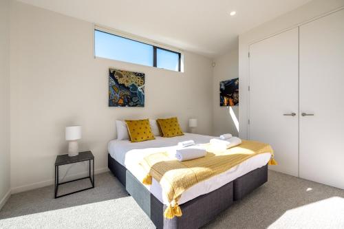 a bedroom with a bed with yellow pillows and a window at Wavesong Mahe in Onetangi