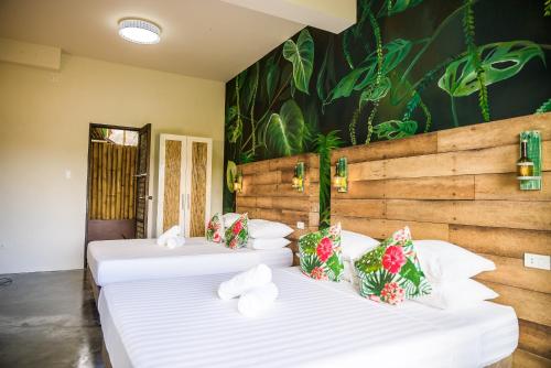 two beds in a room with a wall with plants at Fox & The Firefly Cottages in Loboc