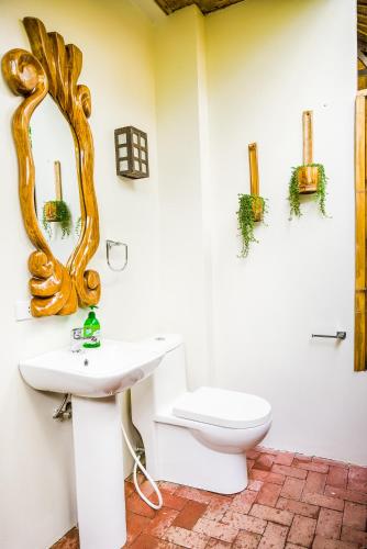 a bathroom with a toilet and a mirror on the wall at Fox & The Firefly Cottages in Loboc