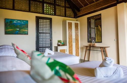 a bedroom with two beds and a table in it at Fox & The Firefly Cottages in Loboc